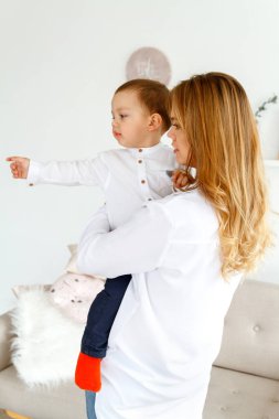 Küçük tatlı bir oğlu olan genç bir anne, parlak, rahat bir oturma odasında eğleniyor.