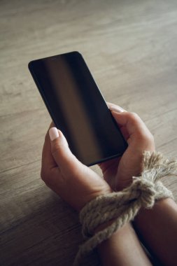 Bağlı kadın elleri bir cep telefonu tutuyor. Akıllı telefon bağımlılığı kavramı.
