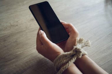 Bağlı kadın elleri bir cep telefonu tutuyor. Akıllı telefon bağımlılığı kavramı.