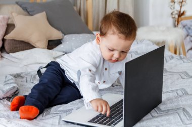 Yatakta dizüstü bilgisayarı olan tatlı bir çocuk.