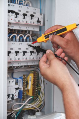 Elektrik şalter dolabında sigorta kutusunu inceleyen çoklu metre sondası olan elektrikçinin elleri