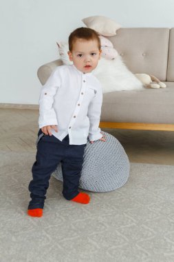 Beyaz tişörtlü şirin bir çocuk parlak, rahat bir oturma odasında oynuyor.