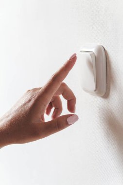 Kadın eli içerideki ışığı kapatır. Enerji tasarrufu kavramı.