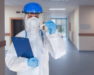 Korunaklı kıyafetli kadın doktor ya da hemşire Coronavirus ya da Cvid-19 için pozitif kan testi sonuçları tutuyor..