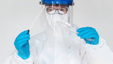 Koruyucu giysili kadın doktor ya da hemşire, laboratuarda koronavirüs kontrolü yapmak için numune alır..