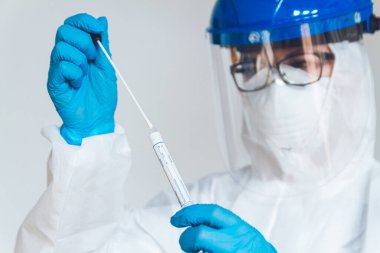 Koruyucu giysili kadın doktor ya da hemşire, laboratuarda koronavirüs kontrolü yapmak için numune alır..