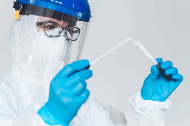 Koruyucu giysili kadın doktor ya da hemşire, laboratuarda koronavirüs kontrolü yapmak için numune alır..