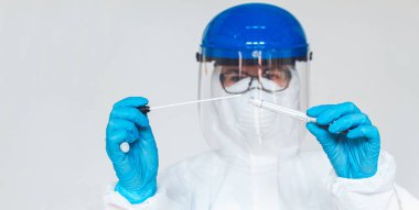 Koruyucu giysili kadın doktor ya da hemşire, laboratuarda koronavirüs kontrolü yapmak için numune alır..