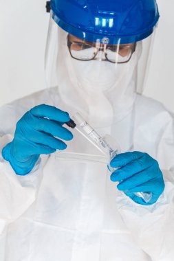 Koruyucu giysili kadın doktor ya da hemşire, laboratuarda koronavirüs kontrolü yapmak için numune alır..