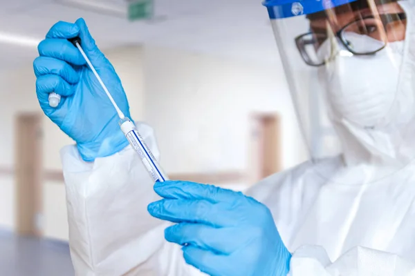 Koruyucu giysili kadın doktor ya da hemşire, laboratuarda koronavirüs kontrolü yapmak için numune alır..
