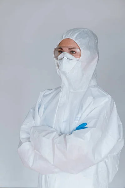 Desperate medical NHS EMS worker in white protective suit,blue surgical  mask latex gloves & safety goggles,Coronavirus COVID-19 pandemic crisis  causing shortage of protective personal equipment supply Stock Photo