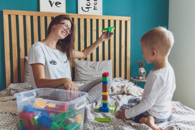 Anne ve çocuk yatak odasında plastik bloklu bir yatakta birlikte oynuyorlar.