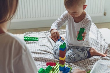 Anne ve çocuk yatak odasında plastik bloklu bir yatakta birlikte oynuyorlar.
