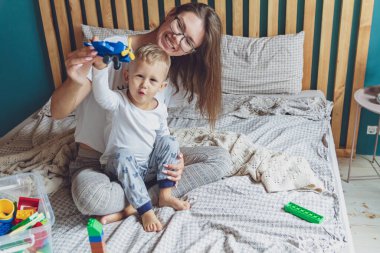 Anne ve çocuk yatak odasında plastik bloklu bir yatakta birlikte oynuyorlar.