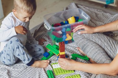Anne ve çocuk yatak odasında plastik bloklu bir yatakta birlikte oynuyorlar.