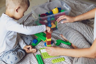 Anne ve çocuk yatak odasında plastik bloklu bir yatakta birlikte oynuyorlar.