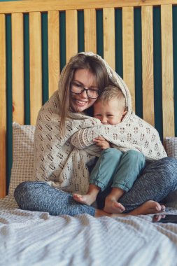Anne ve çocuk yatak odasında, yatağın altında eğleniyor.
