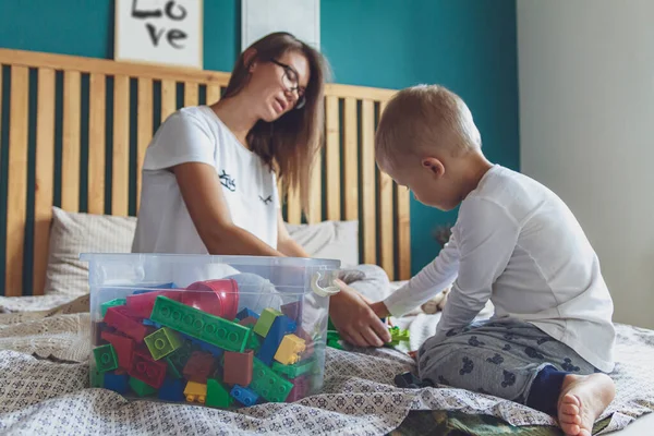 Anne ve çocuk yatak odasında plastik bloklu bir yatakta birlikte oynuyorlar.