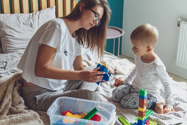 Anne ve çocuk yatak odasında plastik bloklu bir yatakta birlikte oynuyorlar.