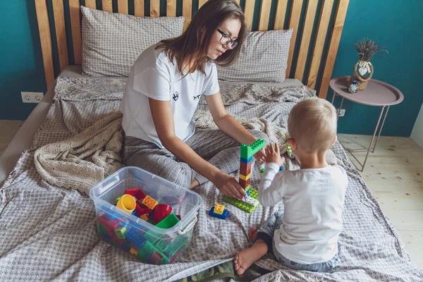 Anne ve çocuk yatak odasında plastik bloklu bir yatakta birlikte oynuyorlar.