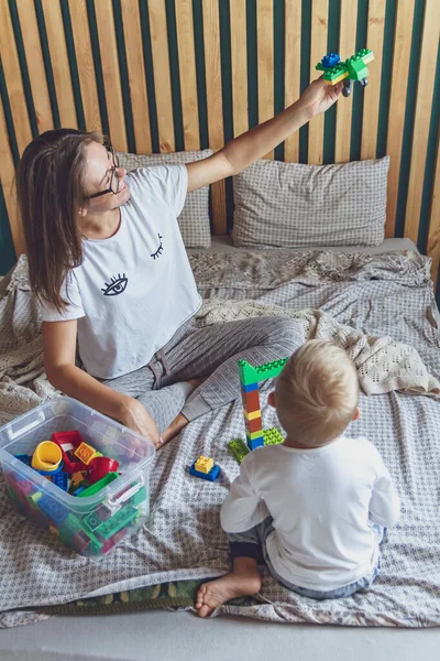 Anne ve çocuk yatak odasında plastik bloklu bir yatakta birlikte oynuyorlar.