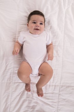 yatakta yatan ve bir kenara bakarak gülen bebek.