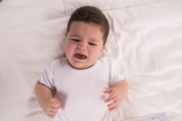 crying baby boy. New born child tired and hungry in bed. Children cry in bed