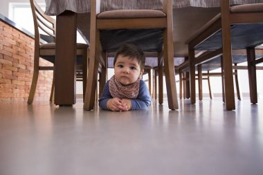 güzel bebek çocuk masanın altında.