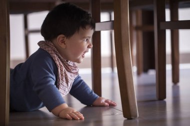 güzel bebek çocuk masanın altında.
