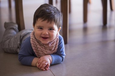 Şirin bebek çocuk kameraya bakarak masanın altına.