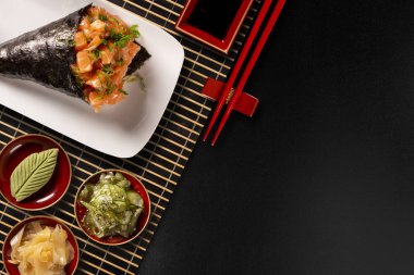 Siyah arka planda beyaz tabakta somon temaki suşisi