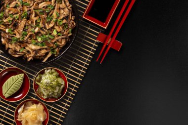 shimeji zencefil, wasabi ve sunomono siyah bir arka plan ile Demir Tavada mantar. Üstten görünüm
