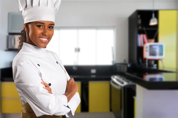 black Brazilian woman chef cooking looking at camera with kitchen blurred in the background.