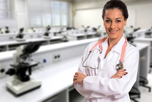 Beautiful smiling doctor woman over microscope room background.