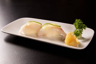 Nigiri Shiromi suşi ile siyah arka plan üzerine beyaz balık.