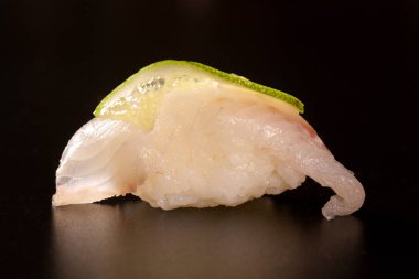 Nigiri Shiromi suşi ile siyah arka plan üzerine beyaz balık.