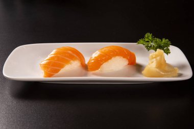 -İyiliği nigiri suşi siyah arka plan üzerine çiğ somon ile.