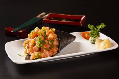 Siyah arka planda beyaz tabakta somon temaki suşisi