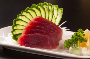 sashimi tuna beyaz bir plaka ile. Siyah bir arka plan üzerinde