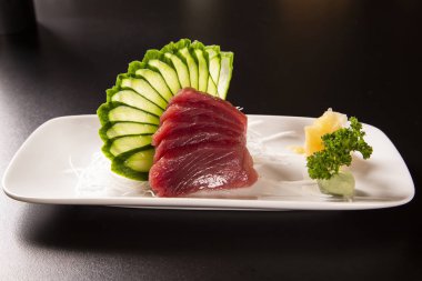 sashimi tuna beyaz bir plaka ile. Siyah bir arka plan üzerinde