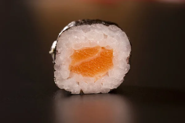 Japanese cuisine. One peace of sushi roll isolated on black background Closeup shot.