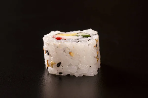 Japanese cuisine. One peace of sushi roll isolated on black background Closeup shot.
