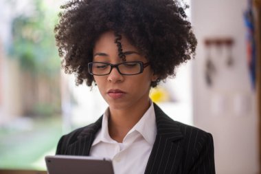 Başarılı genç Afrikalı-Amerikalı iş kadını ev ofisinde bir dijital tablet üzerinde çalışırken odaklı görünümlü.