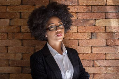 Tuğla duvar arka planda gözlük takan güzel Afrikalı iş kadını.