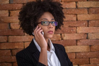 Yakın portre siyah iş kadını çalışanı gözlük ofiste cep telefonu konuşuyor çalışıyor.
