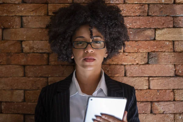 Close up portrait black business woman employee in glasses working in office with tablet looking at camera