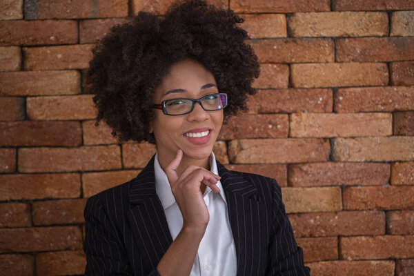 Beautiful African business woman wearing glasses in brick wall background.