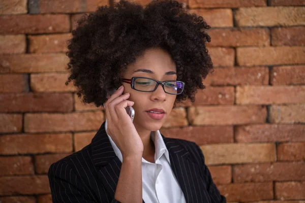 Close up portrait black business woman employee in glasses working in office talking on mobile phone.
