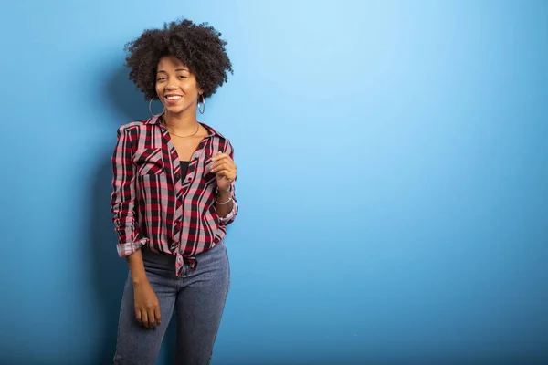 Retrato de una joven negra que ríe contra la pared azul — Foto de Stock