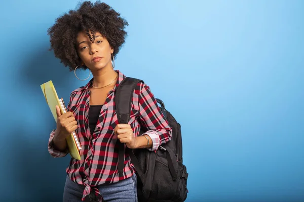 Joven estudiante africano con mochila en la espalda sobre fondo azul . — Foto de Stock